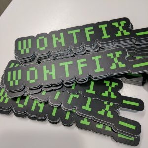 Pile of stickers that read "wontfix_" in green monotype font on a black background.